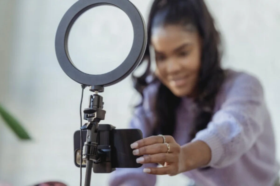 Wanita menyiapkan smartphone dengan ring light untuk membuat konten