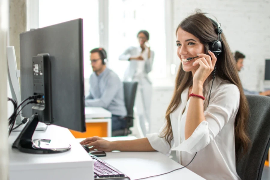 Woman talking to customer through a headset in front of her computer