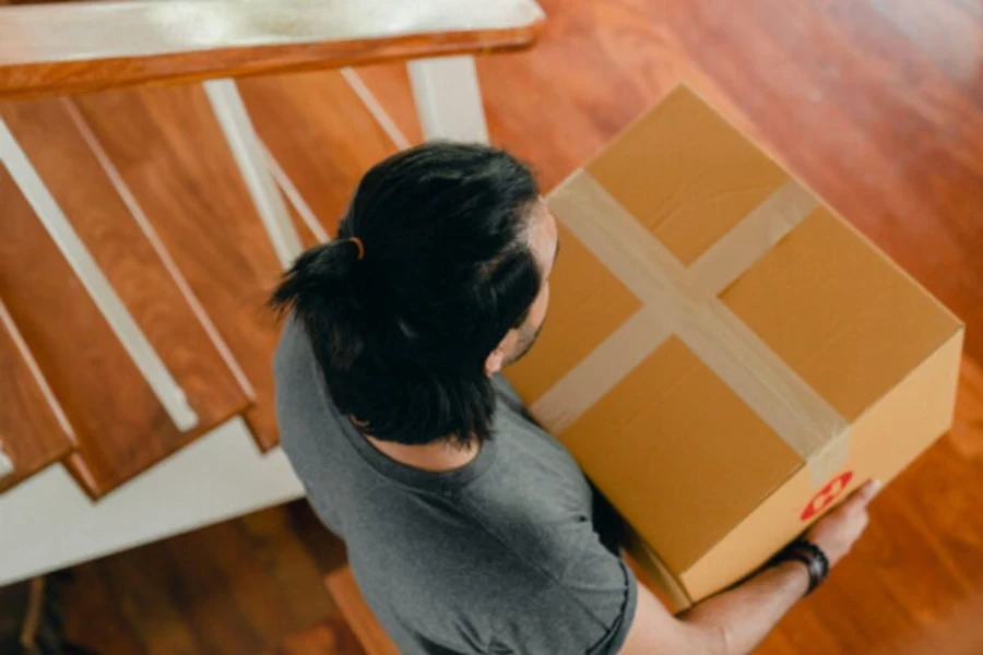 A man carrying a packaged cardboard box into an apartment