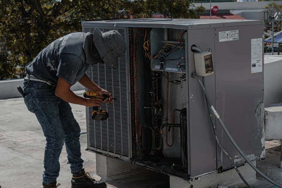 um homem conserta um aparelho de ar condicionado instalado no telhado