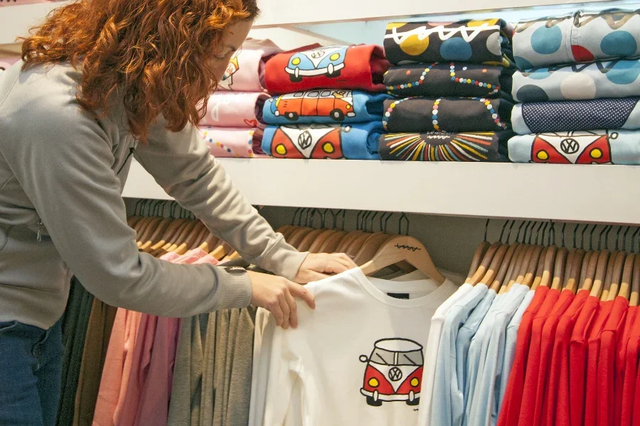 A person hanging a T-shirt in a closet