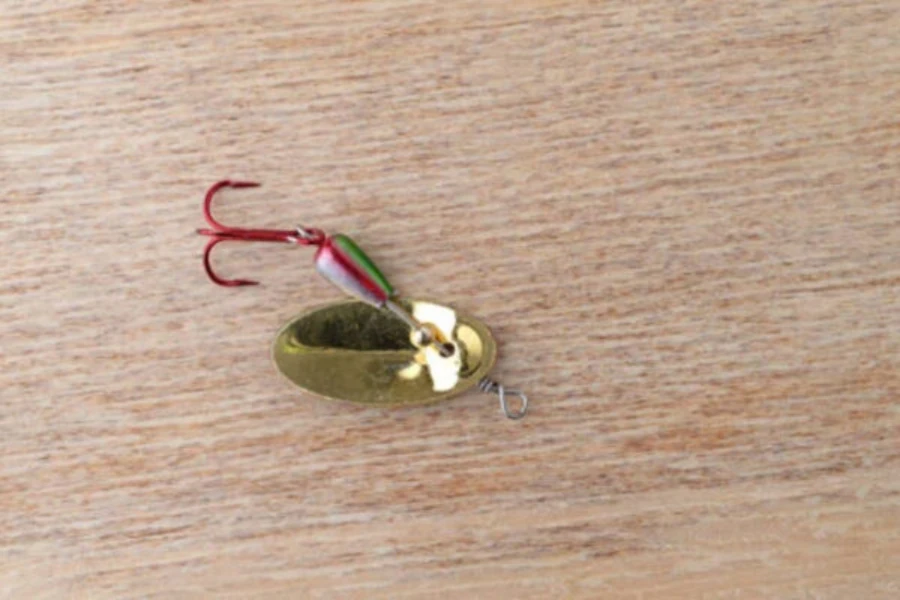 A red and gold metal spoon spinnerbait fishing lure