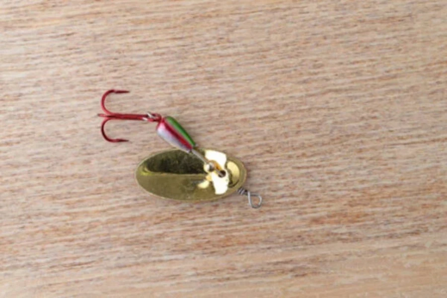 A red and gold metal spoon spinnerbait fishing lure