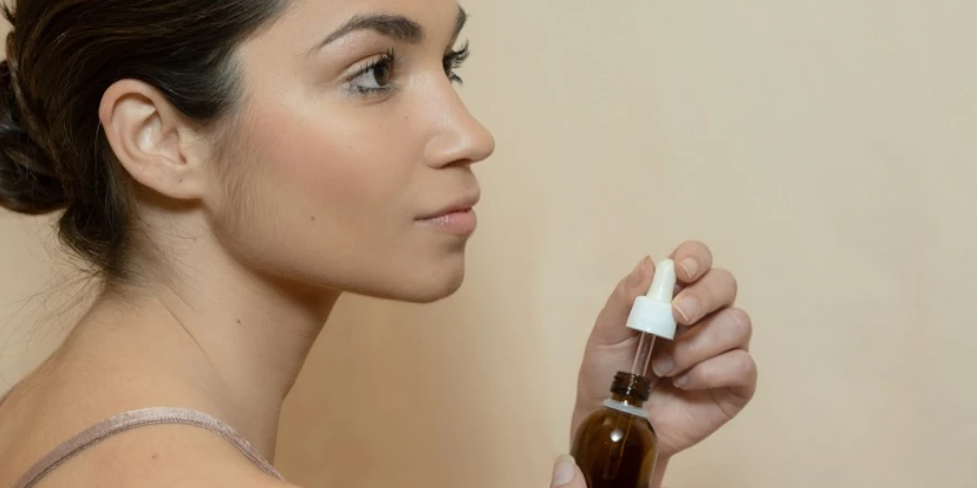 A woman holding a bottle of serum dropper