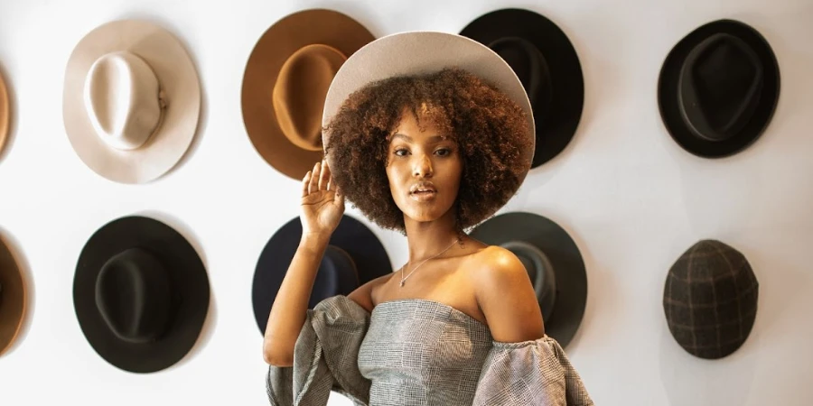A woman in front of a collection of fedora hats