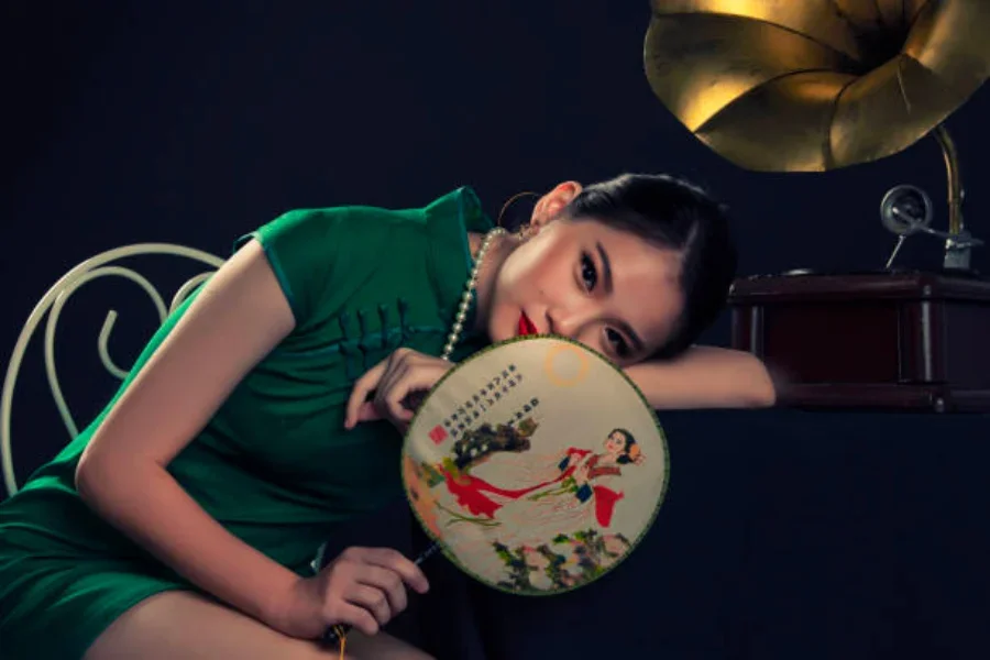 A woman laying her head down on a desk with a woven fan