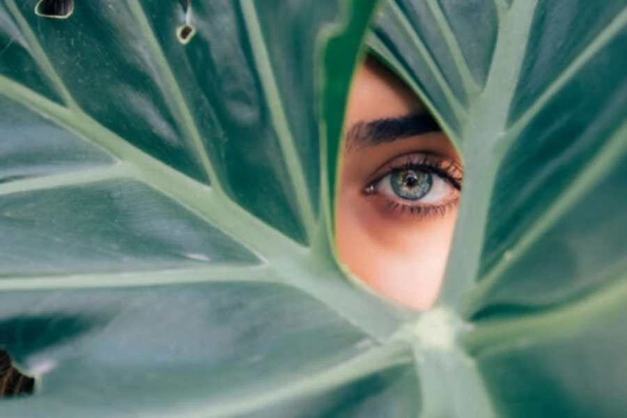 A woman peeking through a green leaf