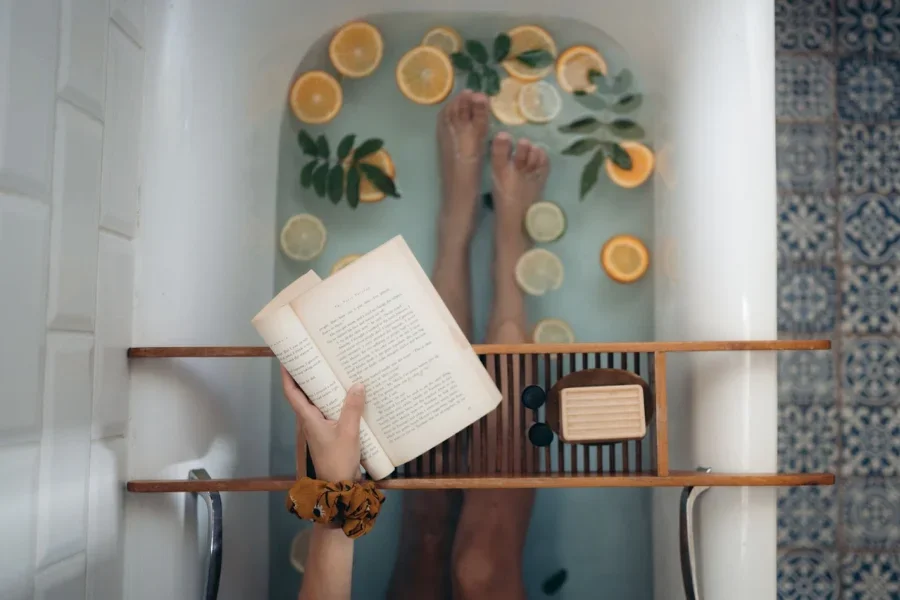Una mujer bañándose y leyendo un libro.