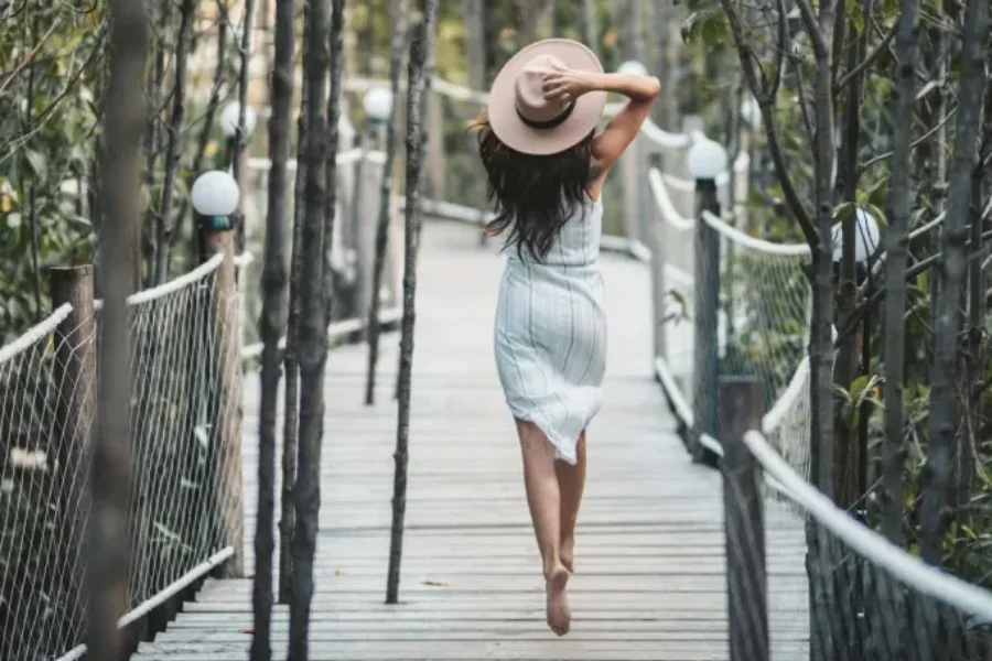 A woman wearing a wide-brim fedora in sunny weather