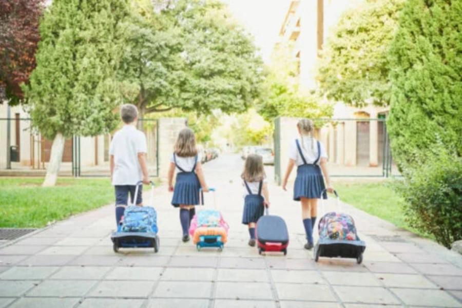 Quatro crianças carregando mochilas em uma área de parque