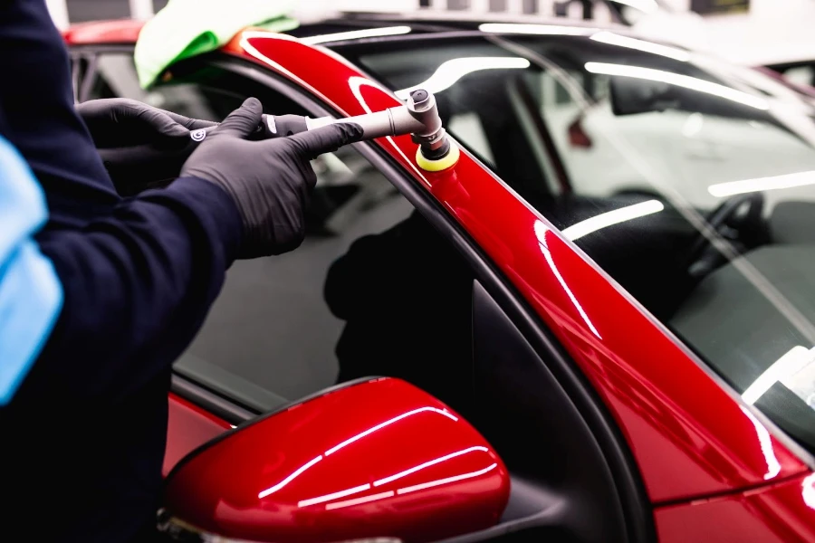 Man with orbital polisher polishing a red car