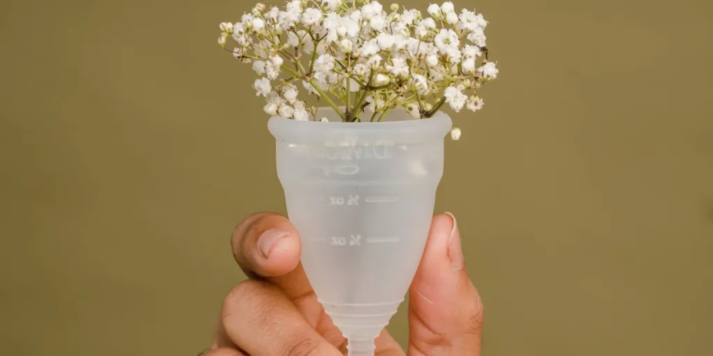 Person holding a white menstrual cup with flowers inside