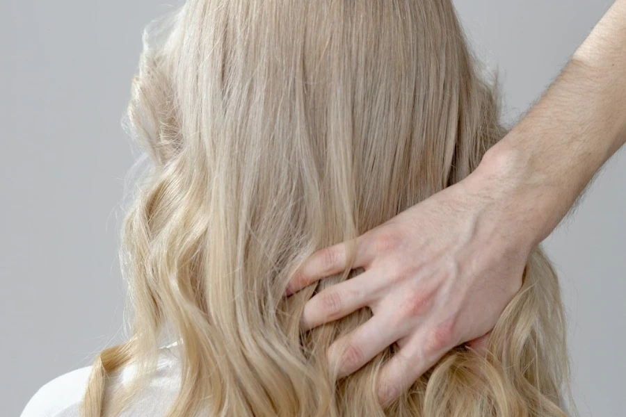 Foto der Hand einer Person, die blondes Haar berührt