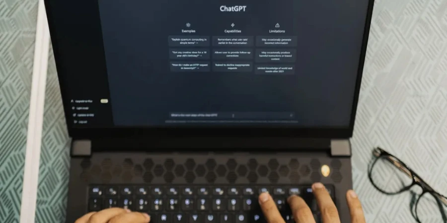 Two hands using a laptop to access the ChatGPT website