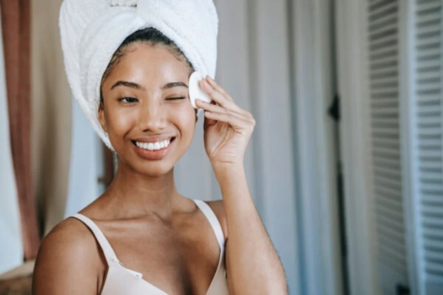 Femme appliquant le produit sur son visage à l'aide d'un rond de coton