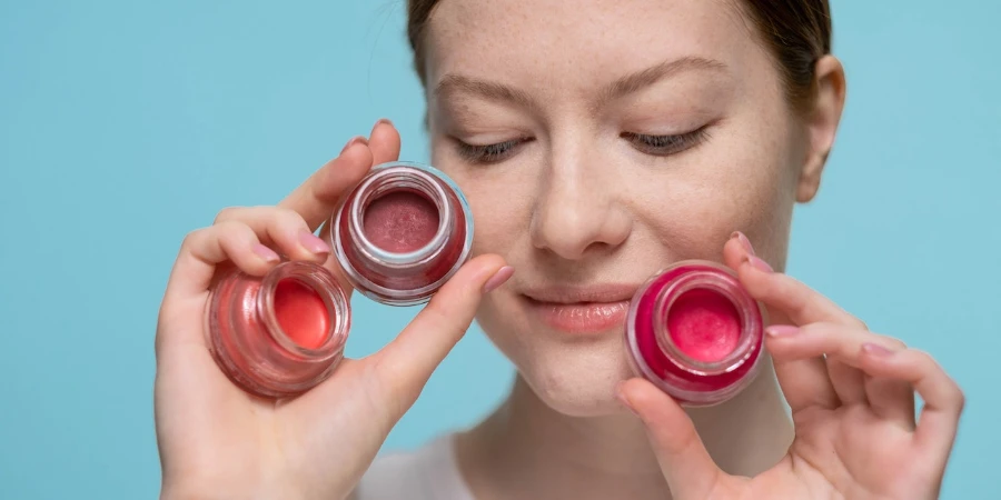 Woman holding glass containers of lipstick with different shades