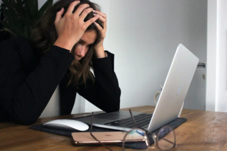 Femme regardant son écran d'ordinateur, attrapant ses cheveux