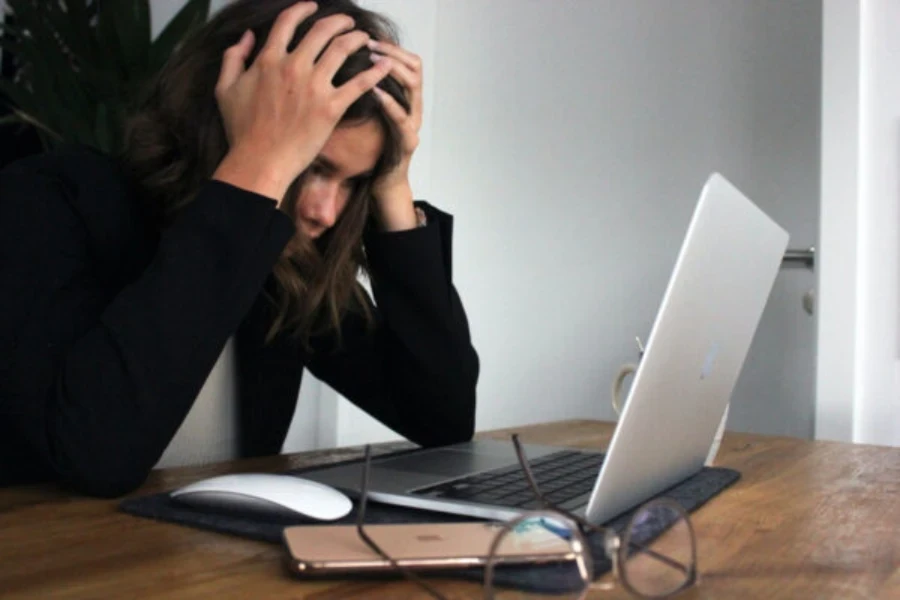 Mulher olhando para a tela do computador, agarrando o cabelo