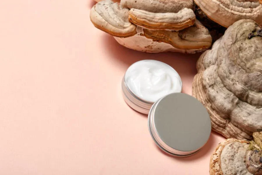 A jar of skin cream sitting next to multiple mushrooms
