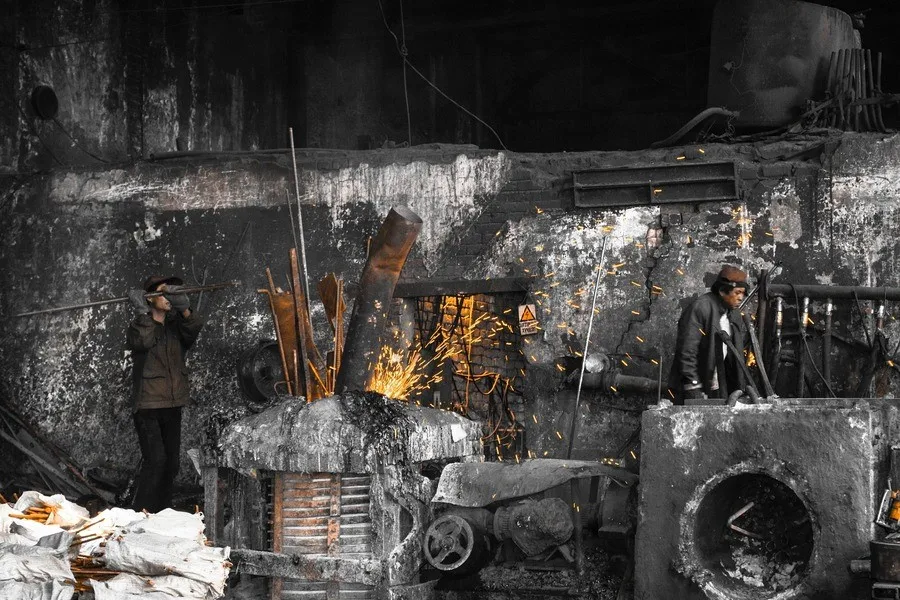 A man standing near a metal furnace