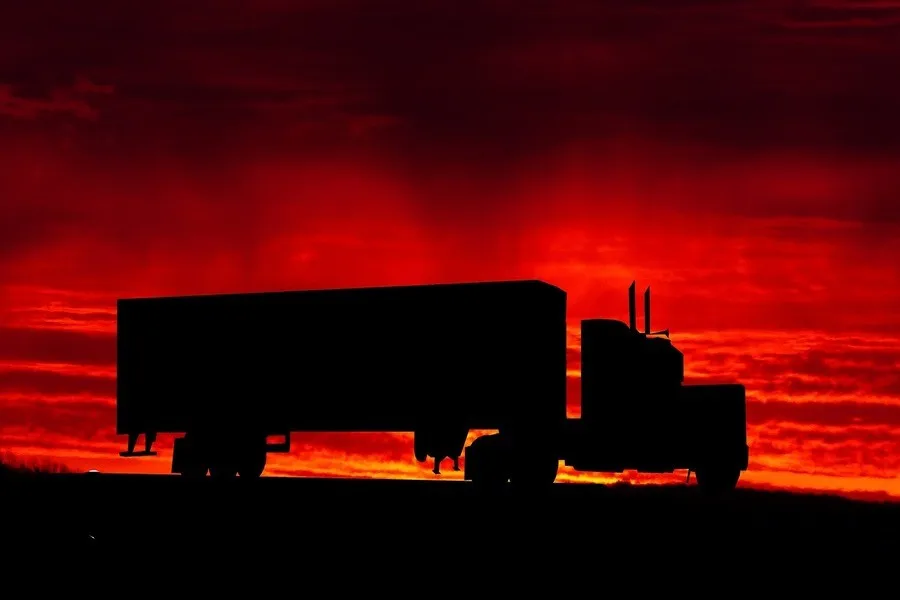 Sebuah truk pengangkut bepergian saat matahari terbenam
