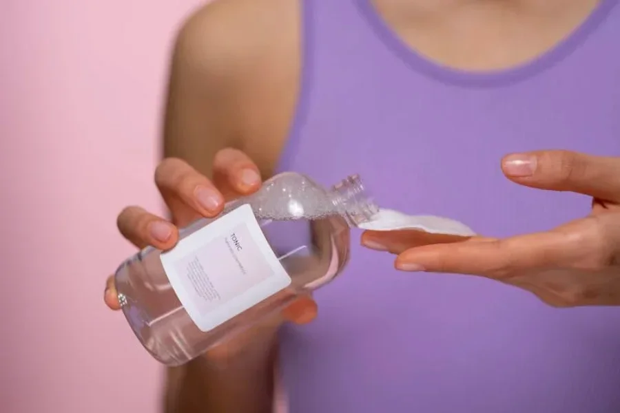 A woman pouring a face serum onto a cotton