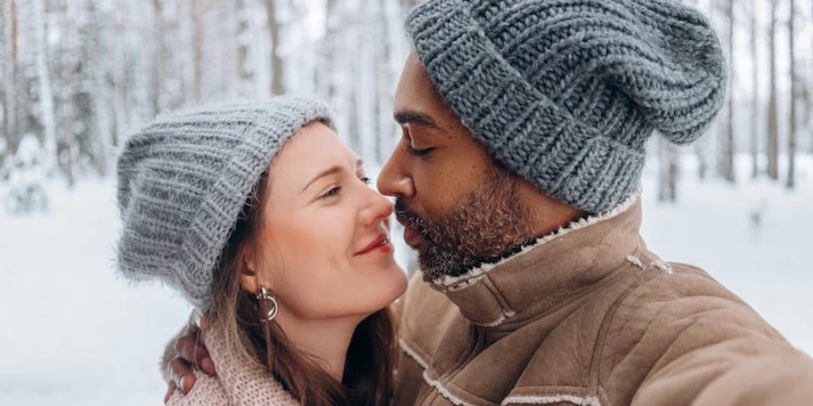 Couple standing outside in the snow wearing winter hats