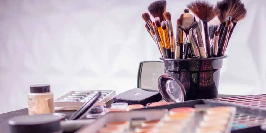 Makeup brushes in a black bucket with eyeshadow palettes
