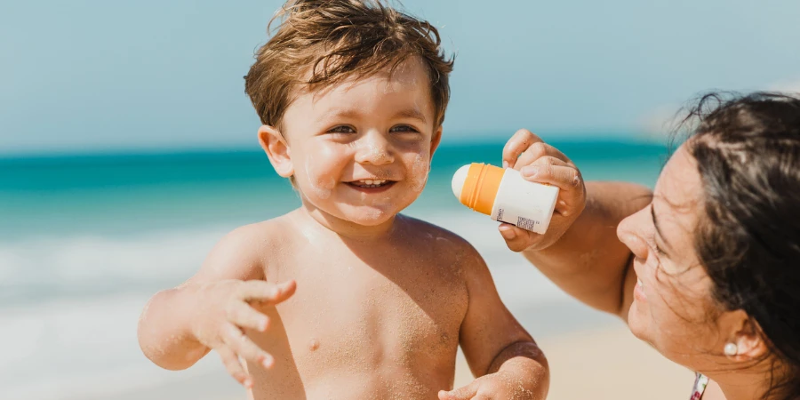 Mother applying sunscreen cream to baby