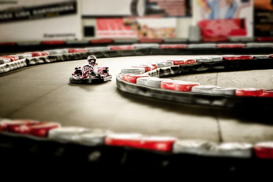 Single go kart driver passing multicolored tires on a track