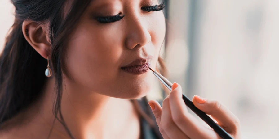 Young Asian woman doing her makeup