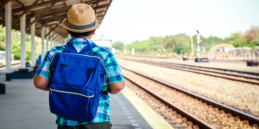 Young boy wearing small blue backpack at train station