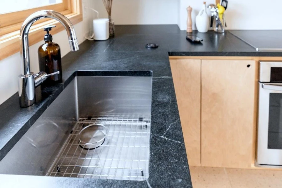 A kitchen sink with natural stone tiled countertop