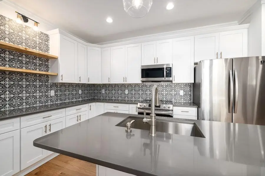 A modern kitchen with grey patterned tile walls