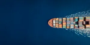 Aerial top down view of a large container cargo ship in motion over open ocean with copy space
