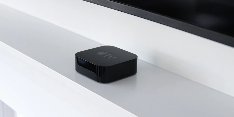 black apple tv step top box on a white shelf under a tv