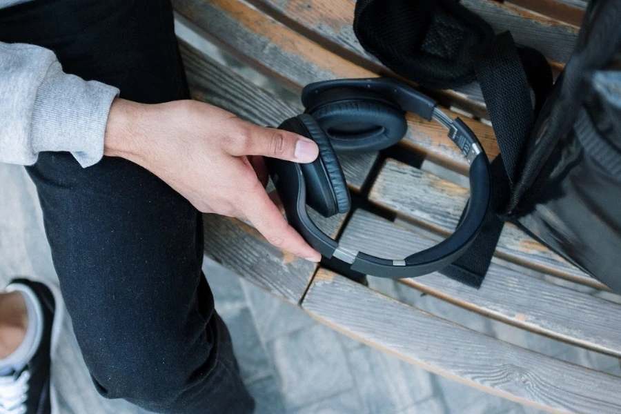 person sitting on a bench holding on ear headphones