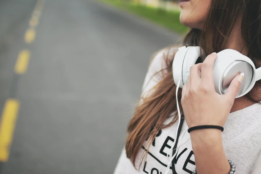 person with long hair wearing over ear headphones around their neck