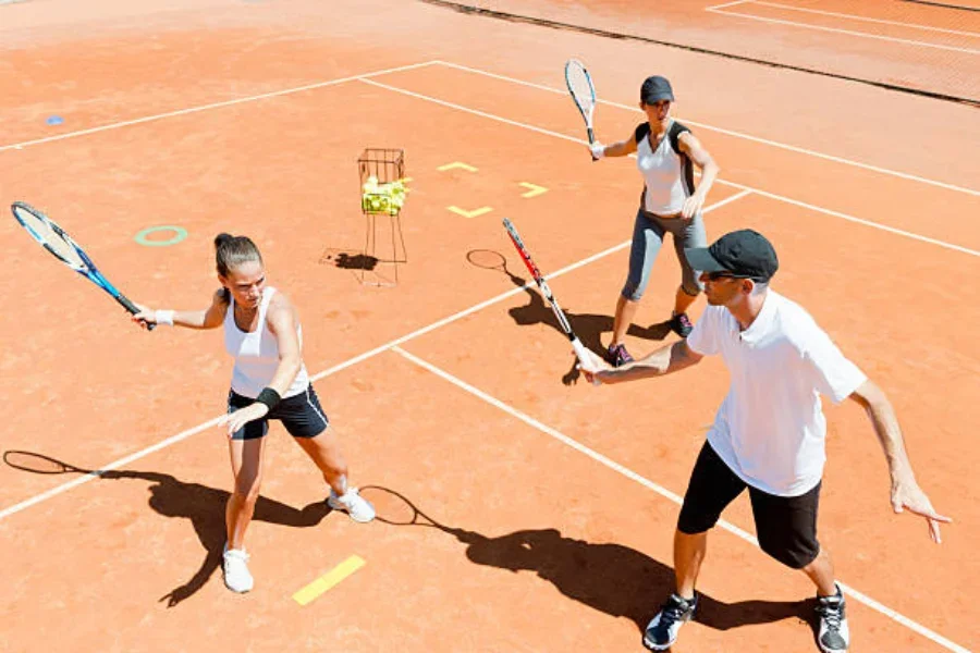 Dos mujeres con entrenador de tenis usando equipo de entrenamiento de tenis