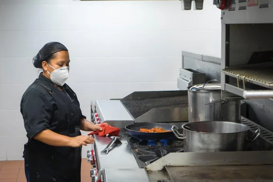 Woman cleaning the top of a silver cookware