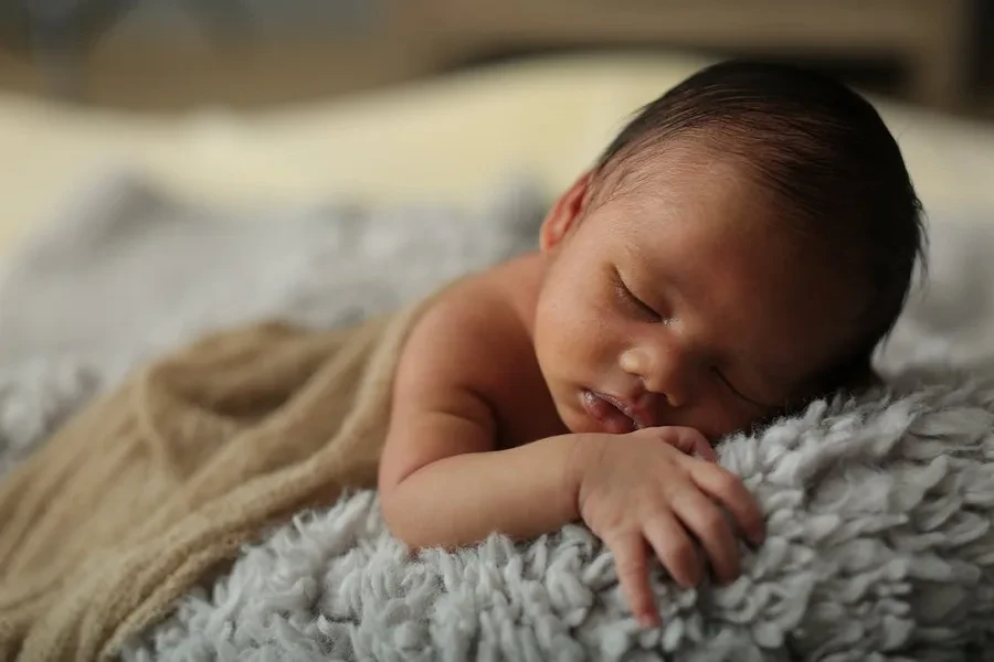 A baby sleeping on a soft, fur-like blanket