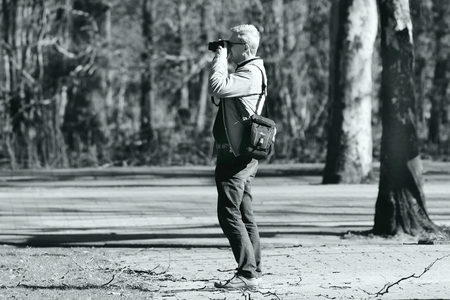 Um homem usando uma câmera com uma bolsa para câmera no ombro