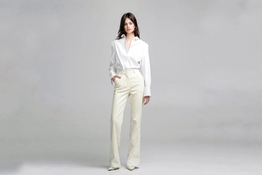 A model in a white button-down shirt and cream patterned pants