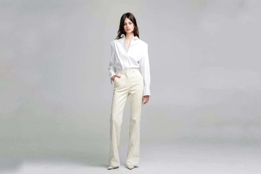 Una modelo con una camisa blanca abotonada y pantalones estampados color crema.