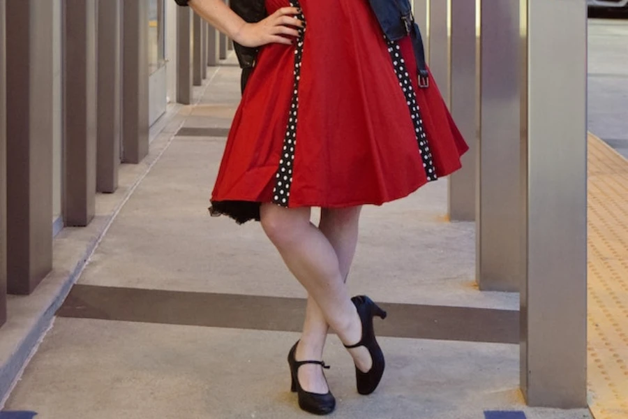 A woman wearing a red dress and black Mary Jane shoes