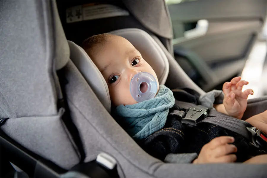 An infant buckled in a baby car seat
