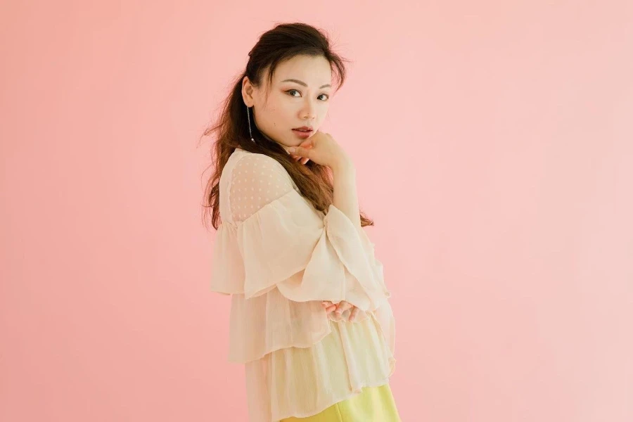 Beautiful lady wearing a yellow sheer top on pink background