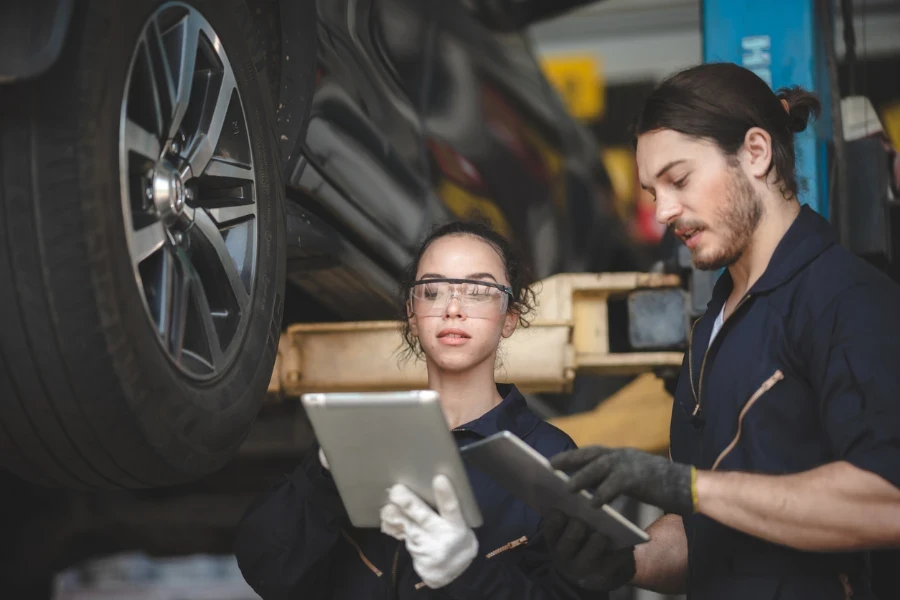 Mecánica femenina con gafas protectoras trabajando debajo de un vehículo