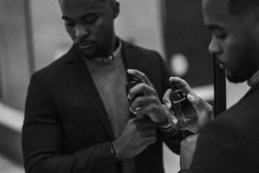 Greyscale photo of a man holding a cologne bottle