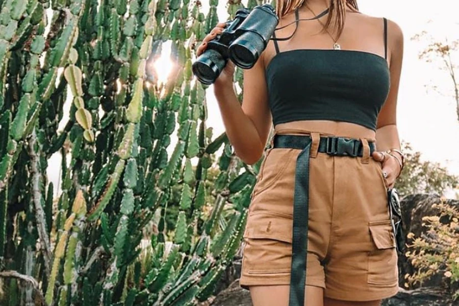 Lady holding binoculars wearing tank top and safari shorts